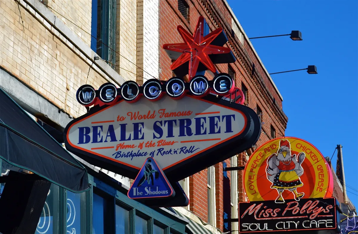 An energetic street scene featuring the iconic Beale Street and Miss Polly's Soul City Cafe signs, a classic Welcome sign, and hints of vibrant local culture. The atmosphere is festive, drawing attention to the dynamic attractions and experiences Memphis is known for, such as live music and unique dining.